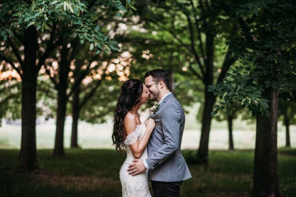 bride and groom kissing with trees in background